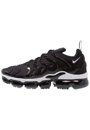 Basket Nike Air VaporMax Plus noir et blanc avec semelle à coussin d'air visible et superpositions au design ondulé sur fond blanc.