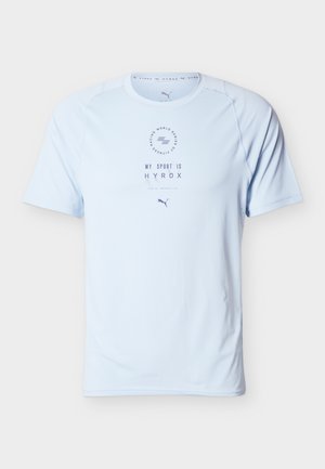 Svetlo modra športna majica s kratkimi rokavi in napisom "MY SPORT IS HYROX", zaobljenim izrezom in logotipom Puma pod napisom.