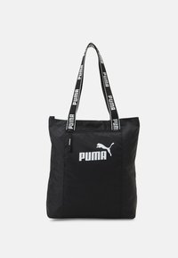 Sac fourre-tout noir en nylon avec une surface texturée, arborant un logo Puma blanc bien visible et des bandoulières marquées. Forme rectangulaire avec fermeture éclair.