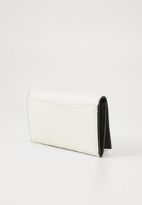Witte leren portemonnee met textuur, voorzien van een opklapbaar ontwerp en zwarte binnenkant; compacte vorm, gladde afwerking en minimalistische accenten.
