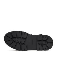 Suela de goma negra con patrones de banda de rodadura profundos y angulares, y acentos de estrella de cinco puntas. Presenta un diseño plano y resistente para ofrecer tracción y durabilidad.