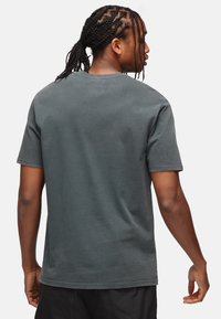 Mørkegrå bomulds t-shirt med korte ærmer, rund hals og en afslappet pasform. Glat tekstur med diskrete sømdetaljer.