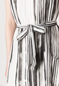 Schwarz-weißer gestreifter Kleid aus durchsichtigem Stoff mit glatter Textur, tailliert mit einem passenden Gürtel.