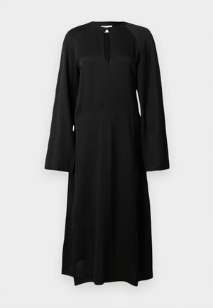 Vestido negro de manga larga hecho de tejido suave, con escote en forma de ojo de cerradura, corte holgado y una silueta ligeramente acampanada.