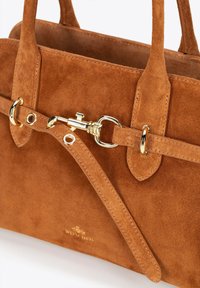 Sac à main en daim marron avec un design structuré, quincaillerie dorée et un détail de sangle avec fermoir. Accentué par un logo.