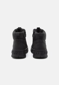 Bottines noires avec une texture douce, dotées de fermetures éclair sur les côtés et d'une semelle en caoutchouc. "TOMMY HILFIGER" embossé sur le talon.
