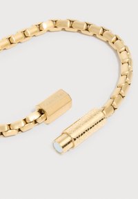 Βραχιόλι αλυσίδας σε χρυσό τόνο με ορθογώνιους κρίκους και κυλινδρικό μαγνητικό κούμπωμα, χαραγμένο με το λογότυπο Calvin Klein σε ένα άκρο.