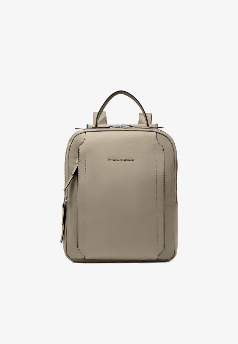 Mochila de cuero beige con dos asas superiores, cierre de cremallera y un logotipo frontal. Presenta un diseño rectangular elegante y detalles visibles de costuras.