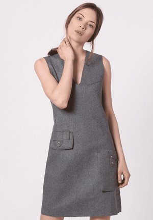 Vestido gris sin mangas con escote en V, hecho de fieltro, que cuenta con dos bolsillos frontales con botones y un diseño minimalista. Textura suave en todo el vestido.