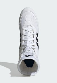 White athletic shoe with mesh fabric, featuring black stripes and a padded collar. Lace-up design with a textured sole and logo accents.