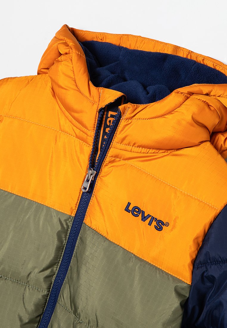 Chaqueta de plumas con bloques de color que presenta secciones en naranja, verde oliva y azul marino. Incluye cierre de cremallera en el frente y capucha forrada de vellón. Logo en el pecho.