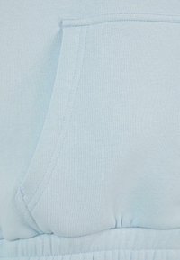 Lyseblå hettegenserstoff med en myk tekstur, med en frontlomme og elastisk midje. Glatt, jevn sømdetalj.