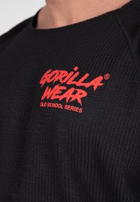 Zwarte sweatshirt met textuur met een rood "GORILLA WEAR" logo en de tekst "OLD SCHOOL SERIES". Ronde halslijn en opvallend geribbeld patroon.