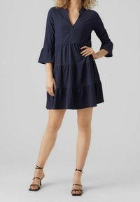 Dunkelblaues Kleid mit V-Ausschnitt, Dreiviertelärmeln und schichten Design. Hergestellt aus strukturiertem Stoff, mit ausgestellten Bündchen und lockerer Passform.