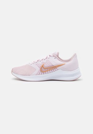 Chaussure de course Nike rose clair avec logo swoosh orange, empeigne en mesh respirant et semelle blanche coussinée, vue de côté sur fond blanc.