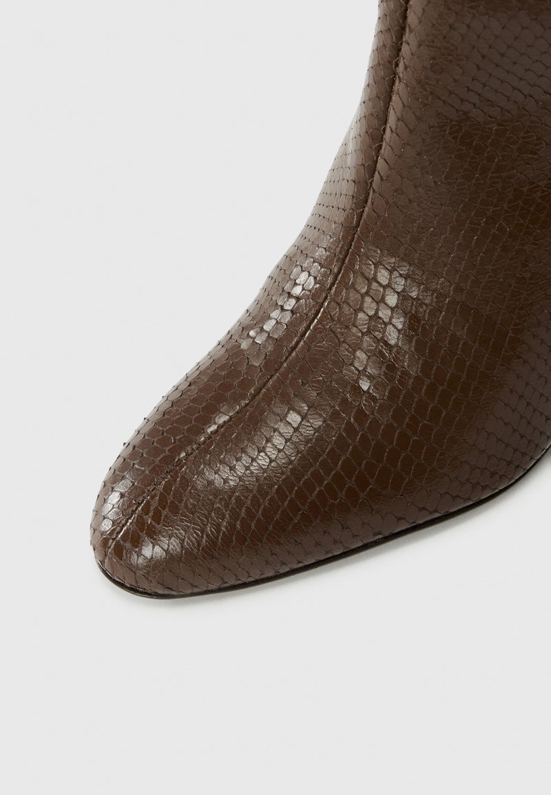 Braun schlangenprägniertes Knöchelboot mit einer spitzen Zehe und glatter Oberfläche. Merkmale dezente Nähte und eine elegante Silhouette.