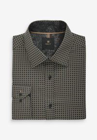 Chemise noire à motifs, ornée de cercles dorés, avec col boutonné, poche poitrine simple, et étiquette avec un design floral à l'intérieur.