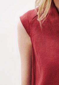 Punainen pellavapaita lyhythihaisilla, jossa on tekstuuri ja huomaamaton olkaintieto, joka esittelee puhtaan ja minimalistisen muotoilun.