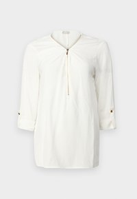 Blusa bianca a maniche lunghe con zip dorata frontale e polsini con bottoni, esposta su uno sfondo chiaro e uniforme.
