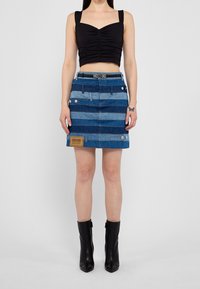 Denimkjol med växlande blå och ljusblå ränder, framfickdetaljer och en Moschino Jeans-etikett i fållen. Kombinera med en svart crop top.