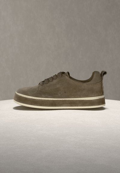 Καφέ καστόρινο sneaker χαμηλού προφίλ με παχύ λευκό περίγραμμα στη σόλα, στρογγυλεμένη μύτη, κλείσιμο με κορδόνια και ταινία έλξης στη φτέρνα σε ανοιχτή επιφάνεια.