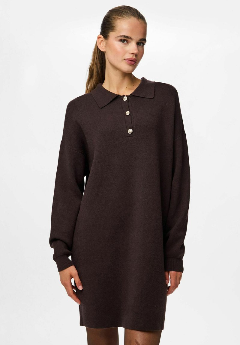 Vestido de punto marrón con un cuello de camisa y cuatro botones decorativos. Presenta mangas largas y un corte relajado, que llega hasta medio muslo.