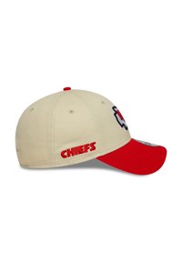 Beige baseball cap with a red visor. Features a Chiefs logo on the front and "CHIEFS" in red embroidery on the side. Textured fabric.