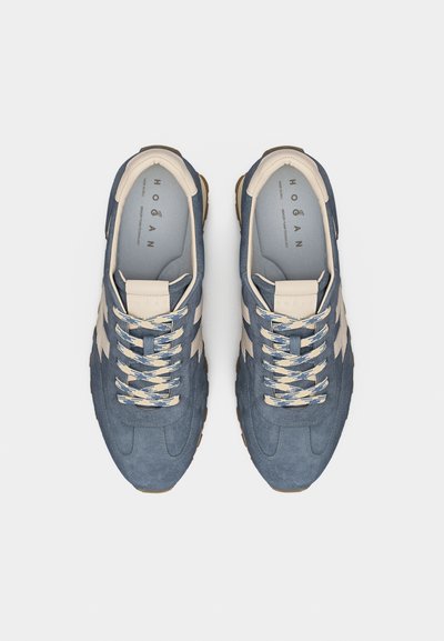 Ζευγάρι μπλε σουέντ αθλητικά παπούτσια με εκρού λεπτομέρειες και κορδόνια με σχέδια, από ψηλά σε απλό φόντο.