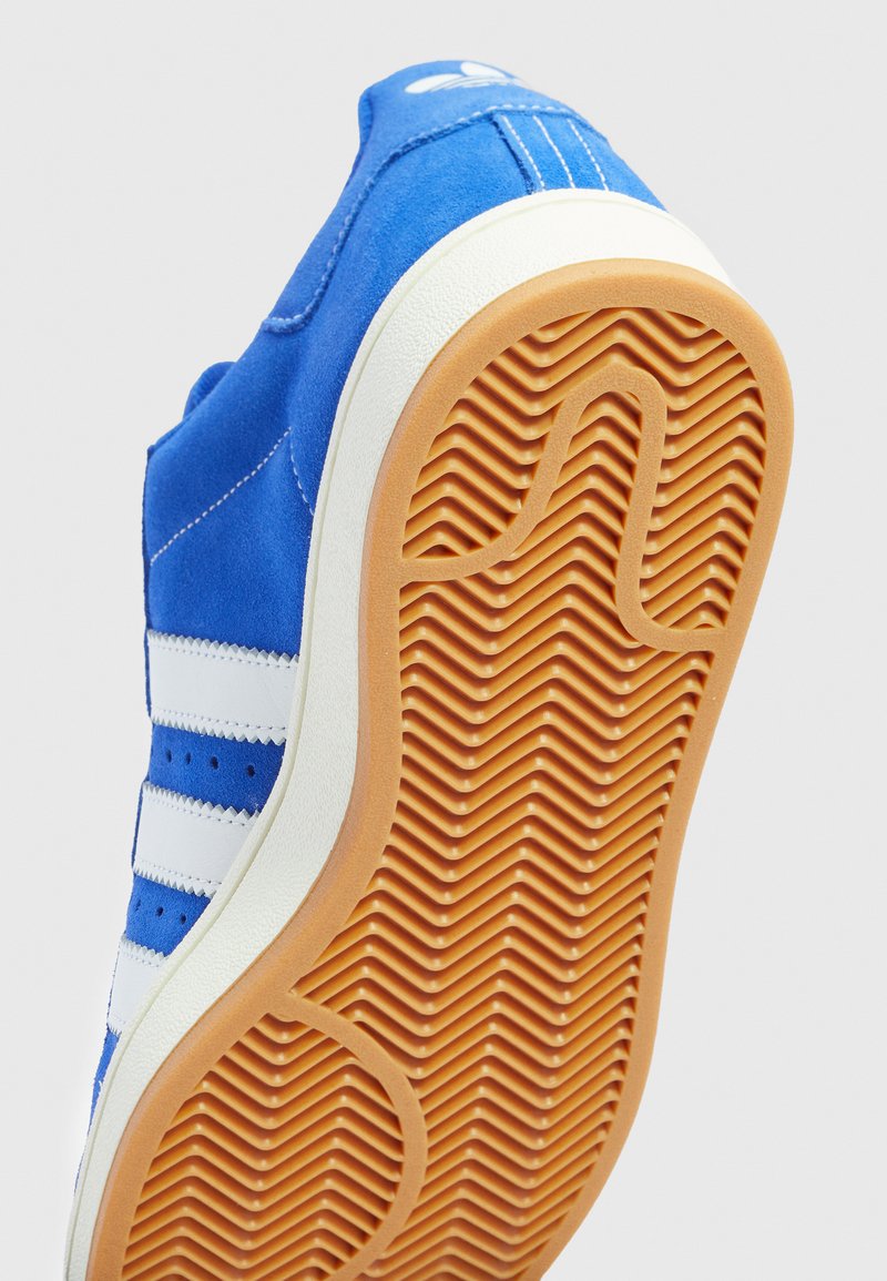 Blaue Wildledersneaker mit weißen Streifen und Nähten. Gummilaufsohle mit Fischgrätmuster für Grip. Klassisches Design, sportlicher Stil.