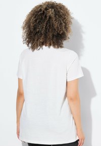 Bílý tričko s krátkým rukávem, vyrobené z měkké bavlny, s volným střihem a kulatým výstřihem. Zadní pohled ukazuje minimální designové detaily a žádné grafiky.