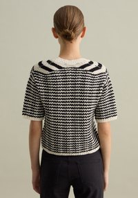 Maglione lavorato a maglia con motivo a righe nero e crema, maniche corte e taglio cropped con una finitura a maglia testurizzata.