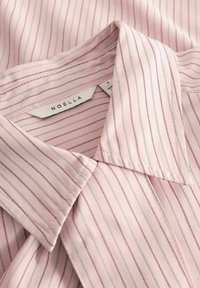 Světlá růžová proužkovaná halenka s klasickým límečkem, jemnými zelenými a hnědými proužky a látkovou štítkem s názvem značky "NOELLA".