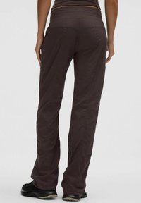 Pantaloni ușori, de culoare marron, cu o textură netedă și o talie ajustată. Partea din spate are cusături subtile și două buzunare laterale.