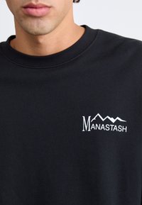 Black sweatshirt featuring a round neck and a white embroidered logo with mountains, located on the left chest area.