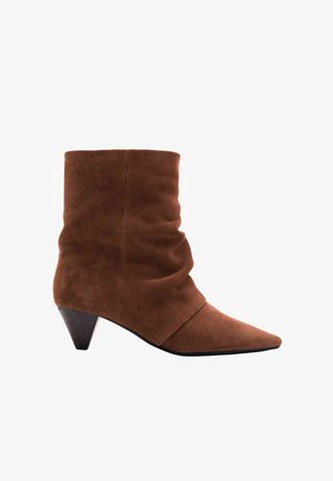 Brun ruskind støvle til anklen med spids snude og lavt, stabler kegleformet hæl, med et let slouchy design.