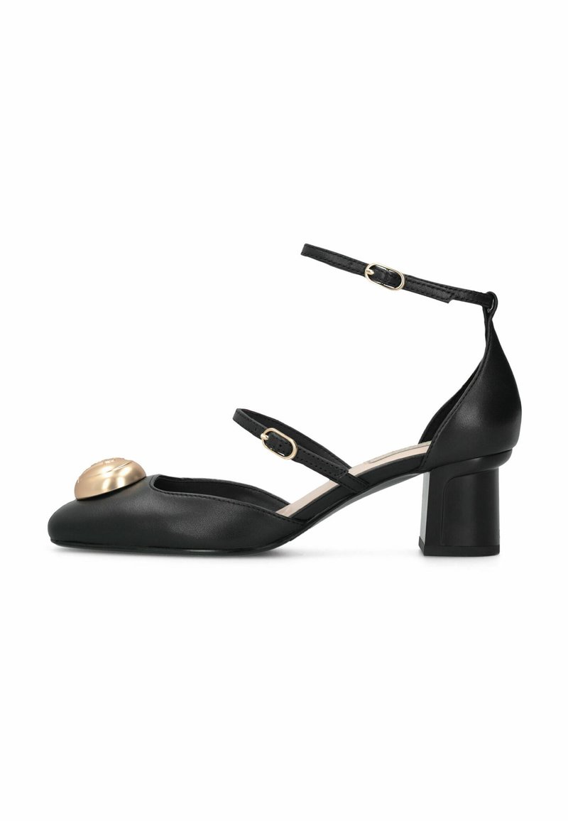 Chaussure à talon haut en cuir noir avec deux brides ajustables à la cheville et un accent rond doré sur le bout. Talon bloc pour plus de stabilité.