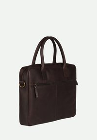 Sac en cuir marron avec doubles poignées, poche avant zippée, design minimaliste et texture lisse. Les accents cousus renforcent la durabilité.