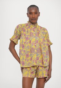 Set di camicia corta a maniche con collo arricciato, in tessuto leggero, di colore giallo con motivi botanici rosa e grigi.