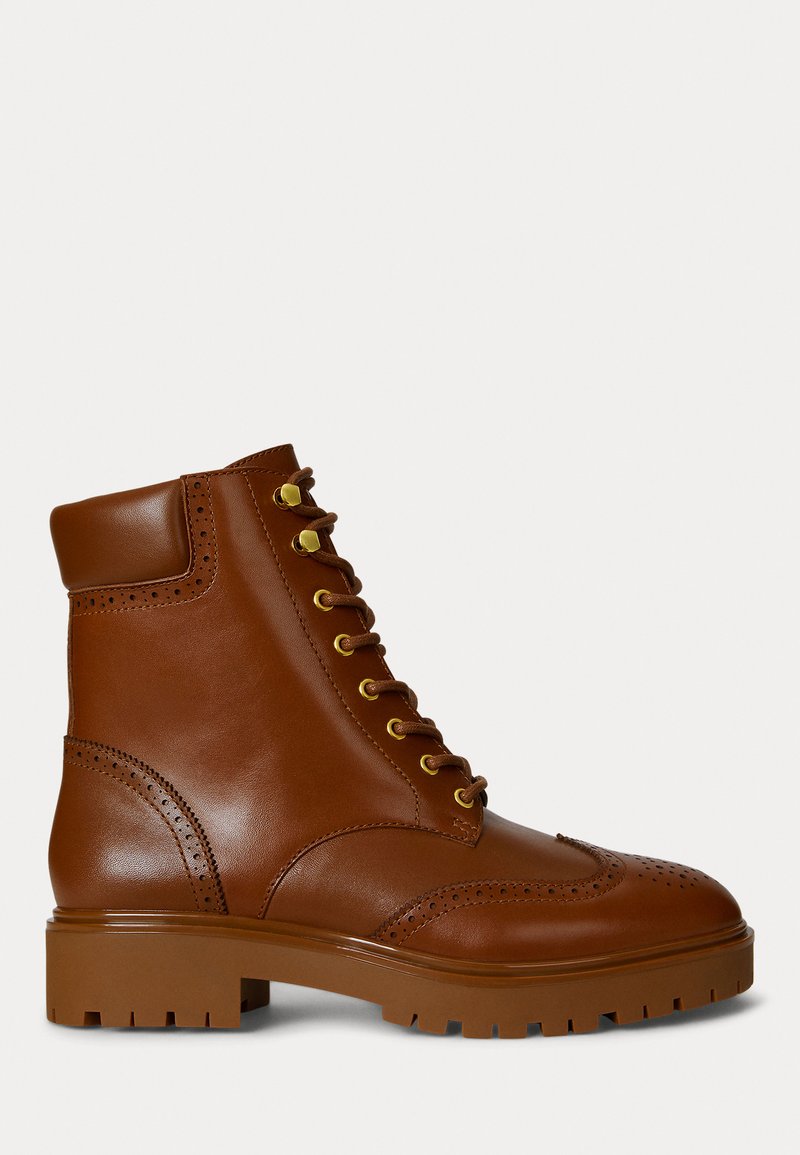 Botas de tornozelo em couro castanho com bico arredondado, ilhós dourados e detalhes de brogue. Sola de borracha castanha grossa com piso texturizado.