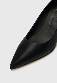 Black leather pointed-toe shoe with a smooth texture and minimal design. Features a low-cut vamp and soft insole for comfort.