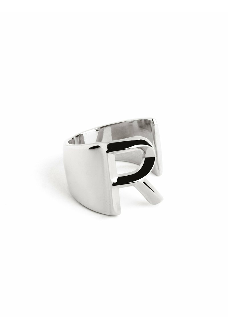 Anello in metallo argento con design a lettera 'R' intagliata, superficie liscia e fascia larga con una forma moderna e minimalista.