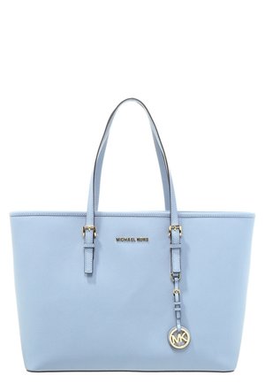 Jasnoniebieska torba typu tote Michael Kors z podwójnymi uchwytami, złotą plakietką z logo i wiszącym charms MK na białym tle.