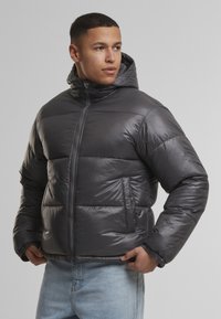 Matinės juodos pūkinės striukės su užtrauktuku, kapišonu ir šoninėmis kišenėmis. Su įsiūtu raštu ir elastingomis rankogaliais.