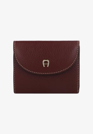 Cartera de cuero burdeos con solapa redondeada, costura superior y un acento de logo metálico dorado en el centro delantero. Diseño compacto y texturizado.