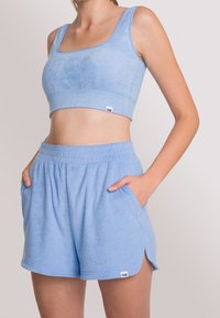 Ljust blått frotté träningsset bestående av en croppad tanktopp med breda axelband och matchande shorts med snörning och sidofickor.