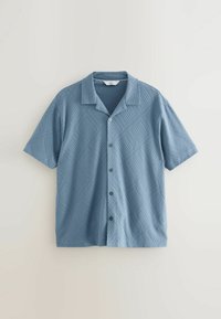 Camisa de manga corta, con botones, en azul claro con un patrón de diamante texturizado. Presenta un cuello tipo camp y botones negros. Tejido mezcla de algodón.