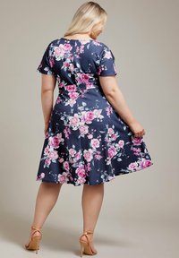 Vestido de manga corta en tejido azul marino con un patrón floral que presenta rosas rosas, cintura ajustada, falda acampanada y una longitud por debajo de la rodilla.