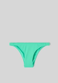 Bas de bikini turquoise en tissu texturé, avec une ceinture élastique et des ouvertures de jambes échancrées sur un fond gris neutre.