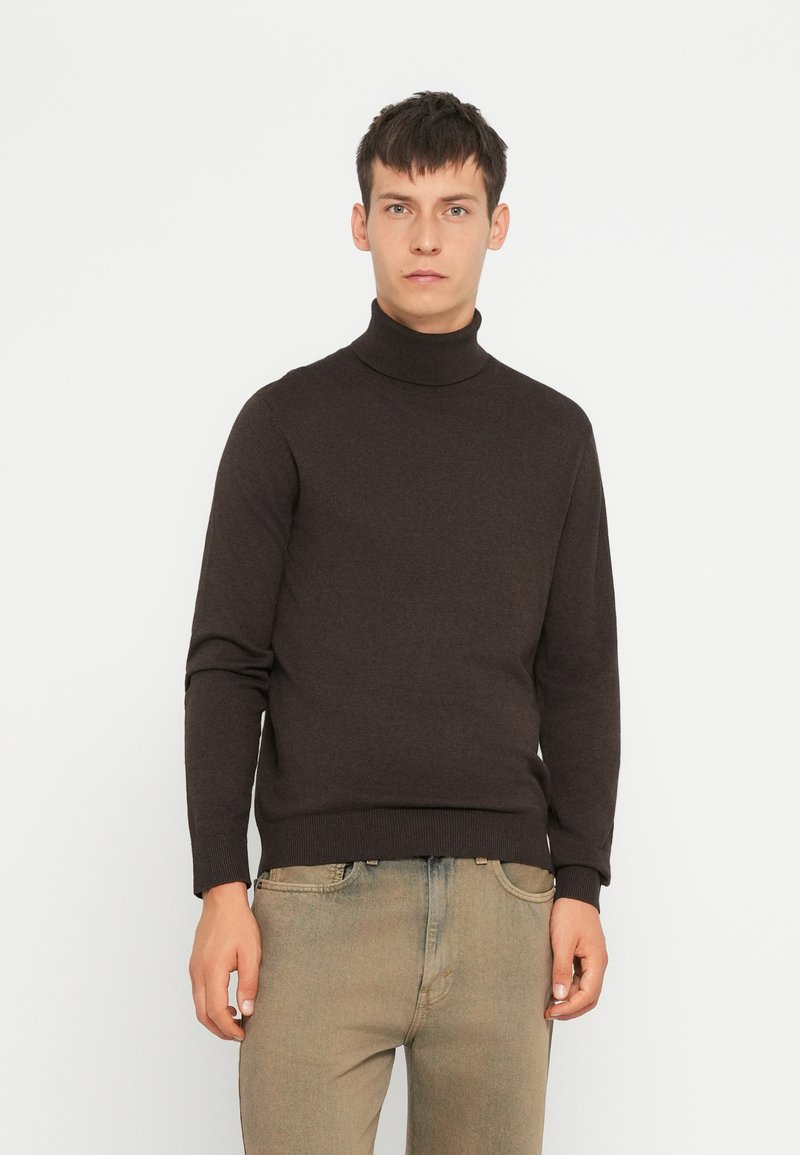 Donkerbruin coltrui van zachte stof, met een aansluitend ontwerp en geribde manchetten. Gecombineerd met lichte jeans.