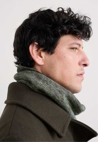 Sciarpa a maglia marrone e verde, con texture a coste, avvolta attorno al collo, abbinata a un cappotto verde oliva scuro, mostrata in profilo.